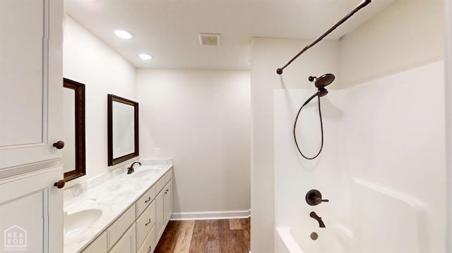 bathroom with wood finished floors, double vanity, a sink, and visible vents