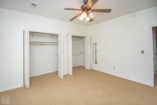 2205 Oak Hollow Ln, Jonesboro, AR 72401 - unfurnished bedroom with multiple closets, light colored carpet, and a ceiling fan
