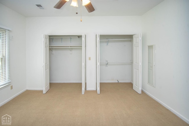2205 Oak Hollow Ln, Jonesboro, AR 72401 - unfurnished bedroom featuring multiple closets, light carpet, and a ceiling fan