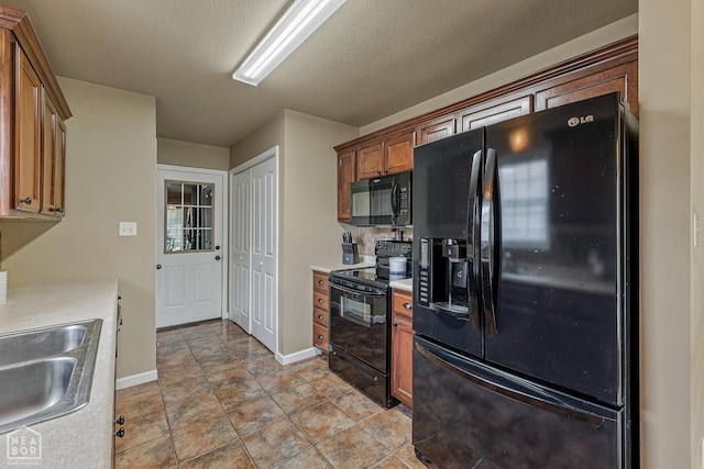 444 Arrowhead Rd, Trumann, AR 72472 - kitchen featuring black appliances, light countertops, brown cabinetry, a sink, and baseboards