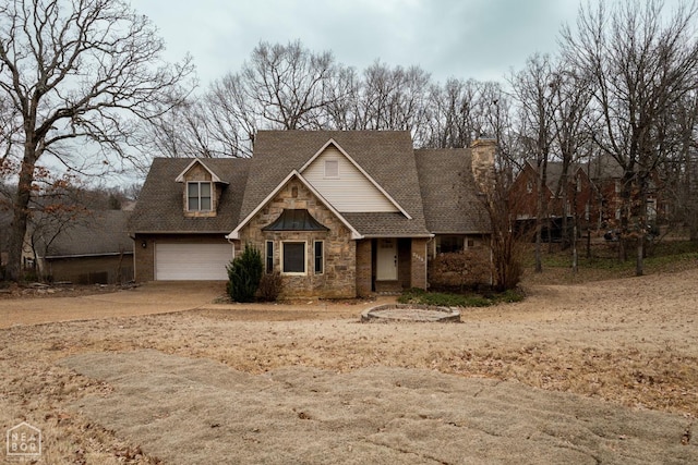 view of front facade with roof with shingles, driveway, and stone siding