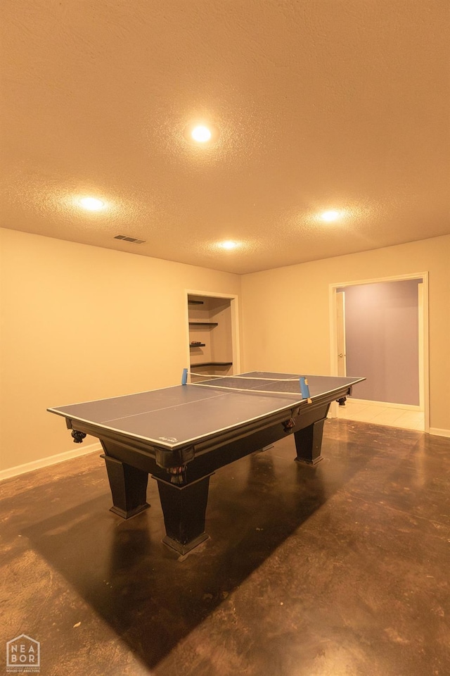 game room with visible vents, baseboards, finished concrete floors, and a textured ceiling
