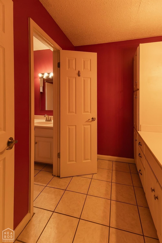 bathroom with tile patterned flooring, vanity, a textured ceiling, and baseboards