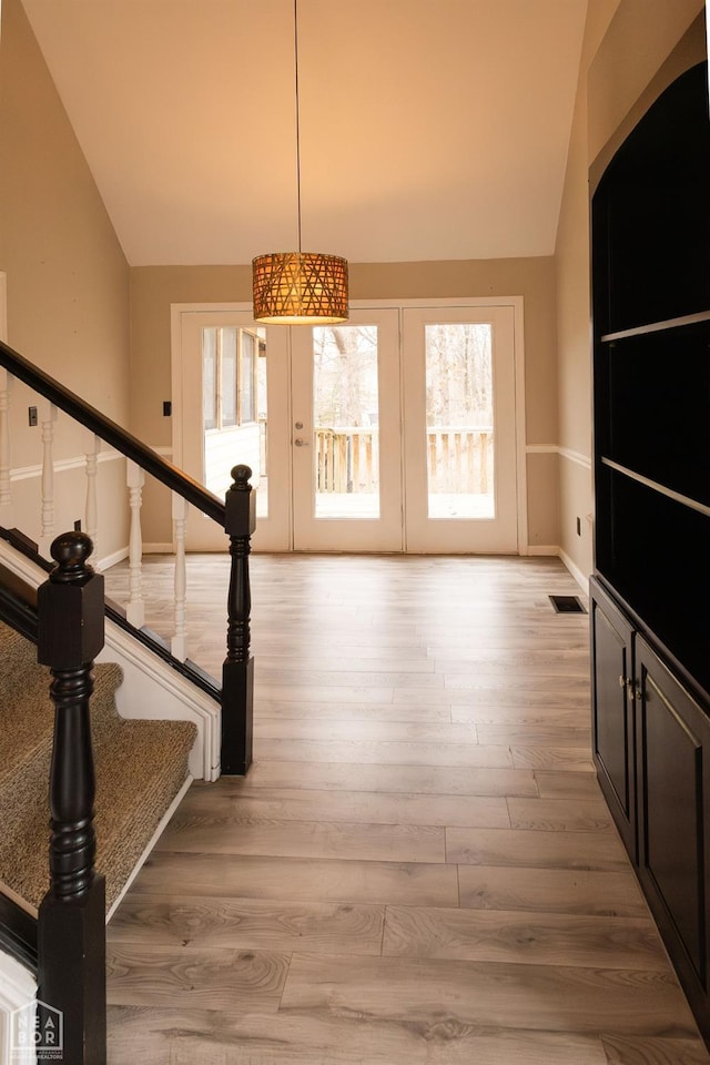 interior space with visible vents, baseboards, wood finished floors, and lofted ceiling