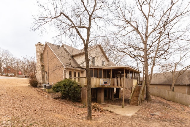 back of house with central AC unit, a sunroom, a chimney, stairway, and a wooden deck