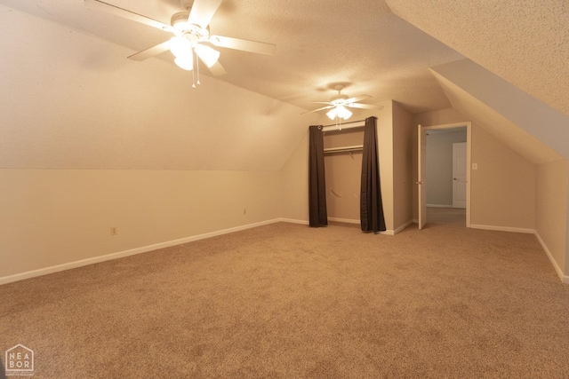 bonus room with baseboards, a ceiling fan, light colored carpet, and a textured ceiling
