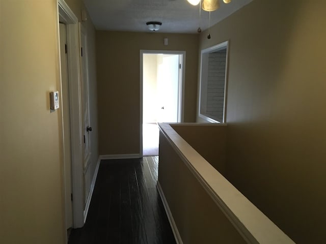 hall featuring baseboards and dark wood finished floors