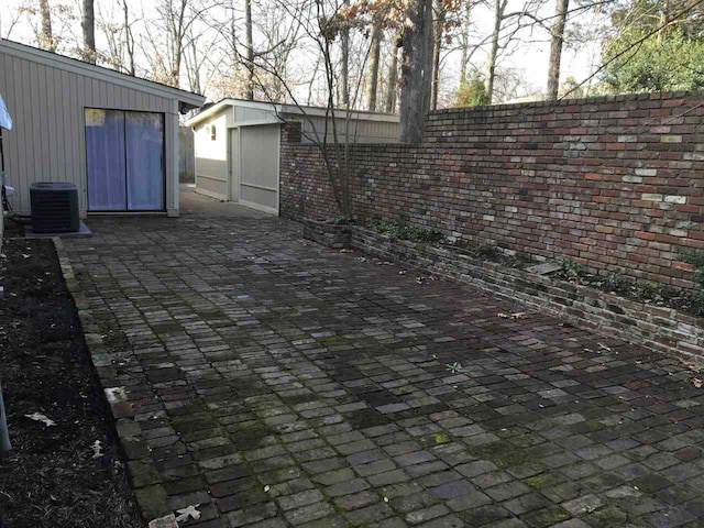 view of patio with fence, an outbuilding, and cooling unit