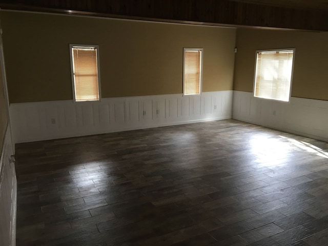 unfurnished room featuring dark wood-style floors and a wainscoted wall