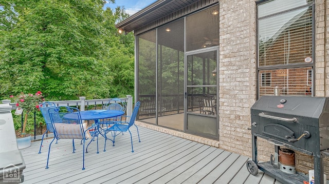 wooden terrace with outdoor dining area, a sunroom, and area for grilling