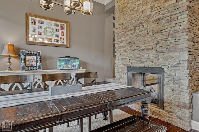 office space with wood finished floors, a chandelier, a stone fireplace, and ornamental molding