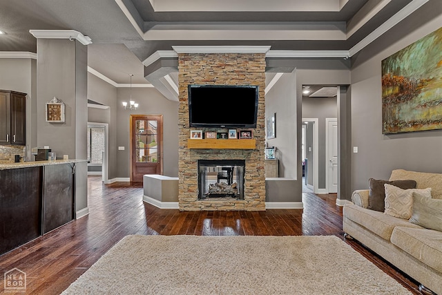 living room featuring dark wood-style flooring, a stone fireplace, baseboards, ornamental molding, and a high ceiling