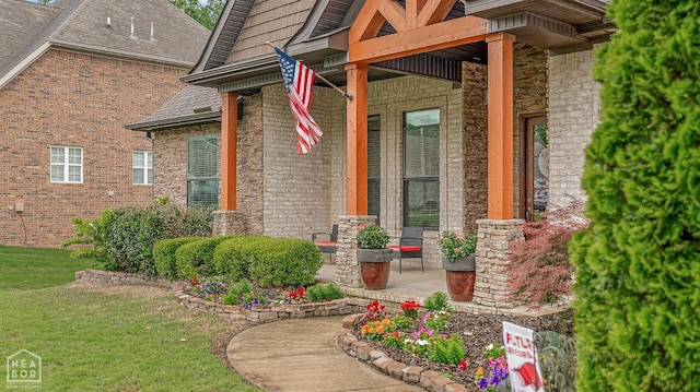 property entrance with a porch, stone siding, a yard, and brick siding