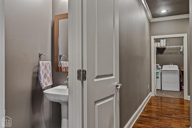 hall featuring ornamental molding, dark wood-style flooring, washing machine and dryer, and baseboards