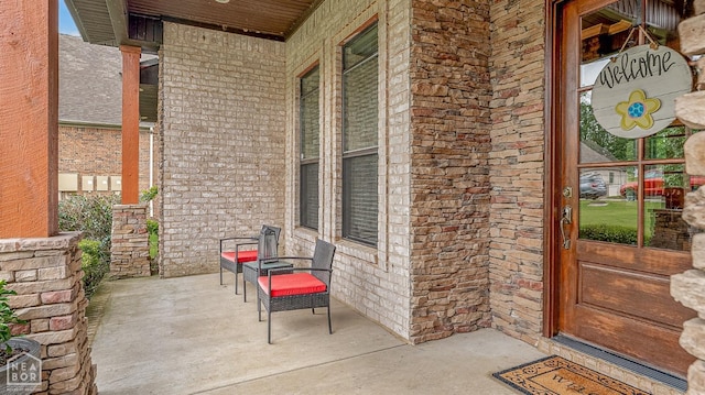 property entrance featuring a porch and brick siding