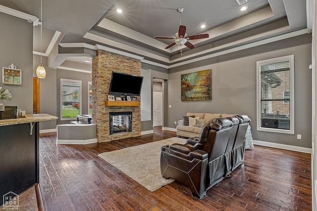 living area featuring a raised ceiling, ceiling fan, baseboards, healthy amount of natural light, and crown molding
