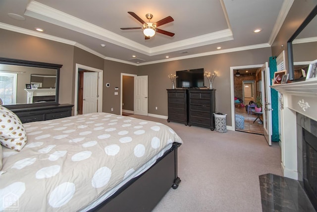 bedroom with a fireplace, carpet, a tray ceiling, and ornamental molding