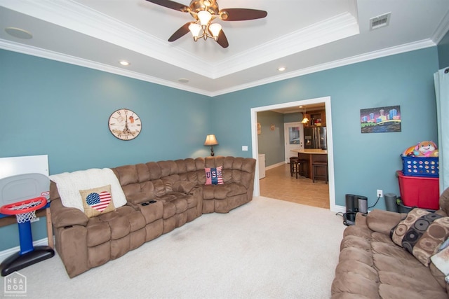 carpeted living room with visible vents, a ceiling fan, crown molding, and a raised ceiling