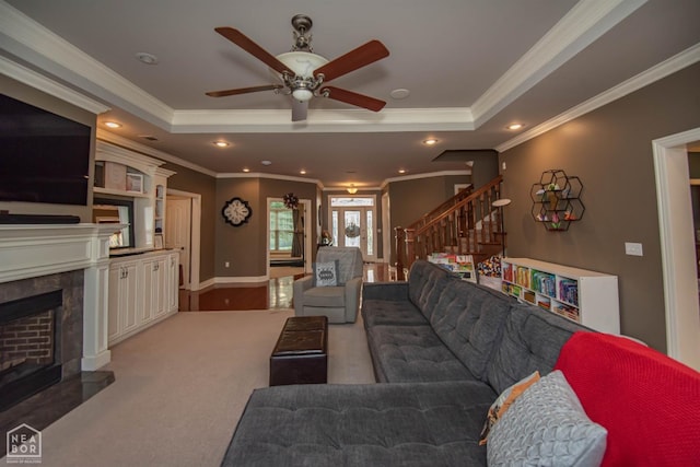 carpeted living area with a raised ceiling, a ceiling fan, a high end fireplace, recessed lighting, and stairs