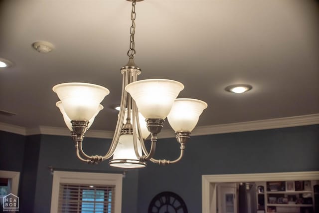 room details featuring ornamental molding and an inviting chandelier