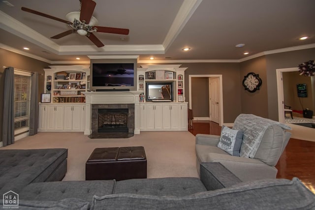 living room with ceiling fan, crown molding, a tray ceiling, recessed lighting, and a fireplace with flush hearth