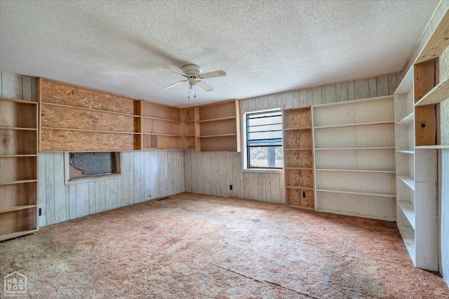 1204 Greene 907 Rd, Paragould, AR 72450 - unfurnished living room featuring carpet flooring, a ceiling fan, wood walls, and a textured ceiling