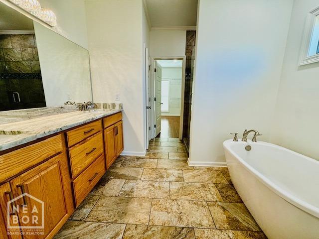 3803 Stone Ridge Dr, Paragould, AR 72450 - bathroom featuring a freestanding bath, double vanity, a stall shower, baseboards, and stone tile flooring