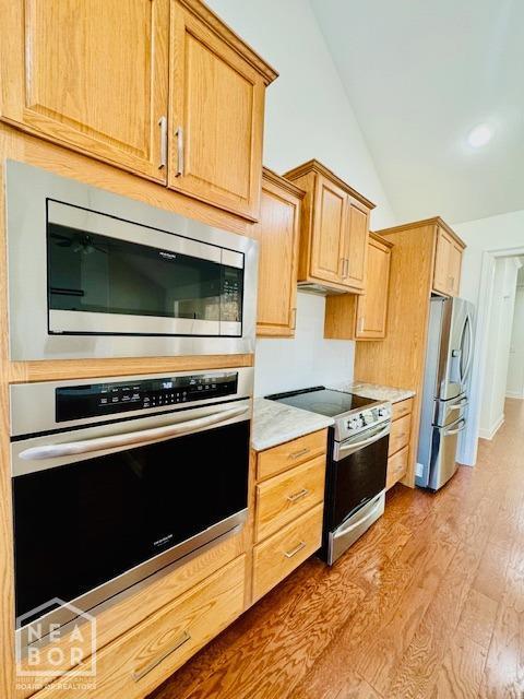 3803 Stone Ridge Dr, Paragould, AR 72450 - kitchen with stainless steel appliances, lofted ceiling, light countertops, and light wood-style floors