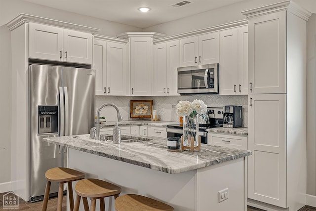 3604 Fieldstone Dr, Paragould, AR 72450 - kitchen featuring appliances with stainless steel finishes, white cabinetry, tasteful backsplash, a breakfast bar area, and recessed lighting