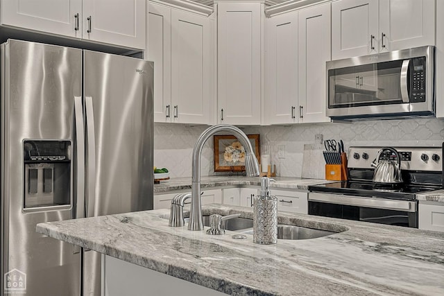 3604 Fieldstone Dr, Paragould, AR 72450 - kitchen featuring stainless steel appliances, white cabinets, decorative backsplash, and light stone countertops