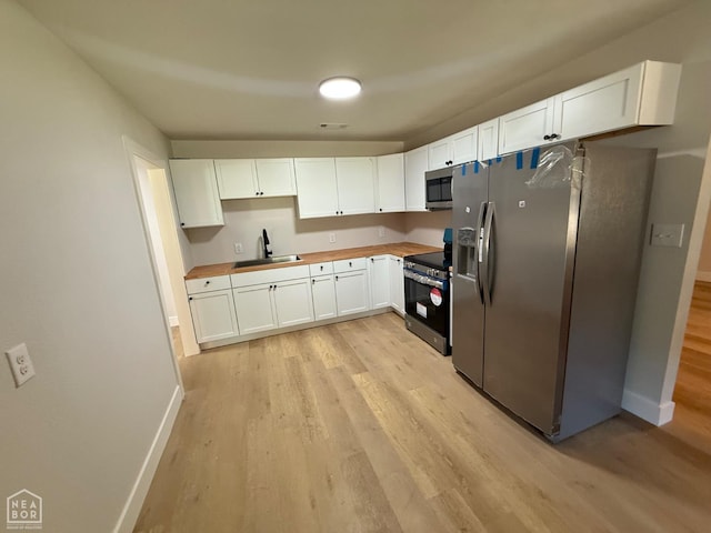 2408 Harper St, Corning, AR 72422 - kitchen featuring stainless steel appliances, light wood-type flooring, and white cabinetry