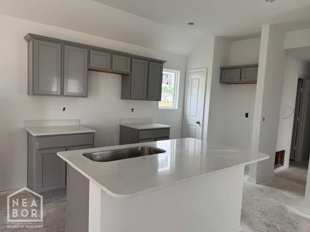 5706 Boone St, Jonesboro, AR 72404 - kitchen featuring a center island, gray cabinets, vaulted ceiling, a sink, and baseboards