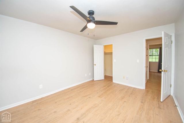 2209 Greensboro Rd, Jonesboro, AR 72405 - unfurnished bedroom with light wood-style flooring, baseboards, ceiling fan, and a walk in closet