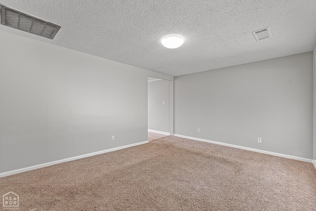 unfurnished room with a textured ceiling, visible vents, carpet flooring, and baseboards