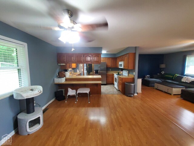 800 Hilltop Dr, Piggott, AR 72454 - kitchen featuring white appliances, a peninsula, open floor plan, light wood finished floors, and a ceiling fan