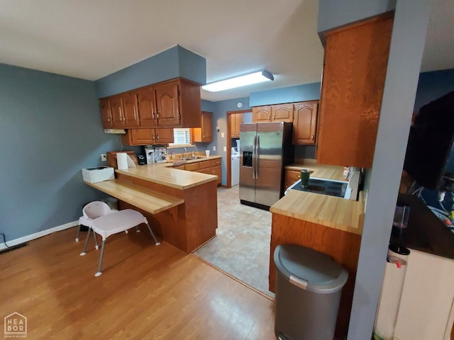 800 Hilltop Dr, Piggott, AR 72454 - kitchen featuring stainless steel fridge, electric stove, a peninsula, brown cabinetry, and a sink