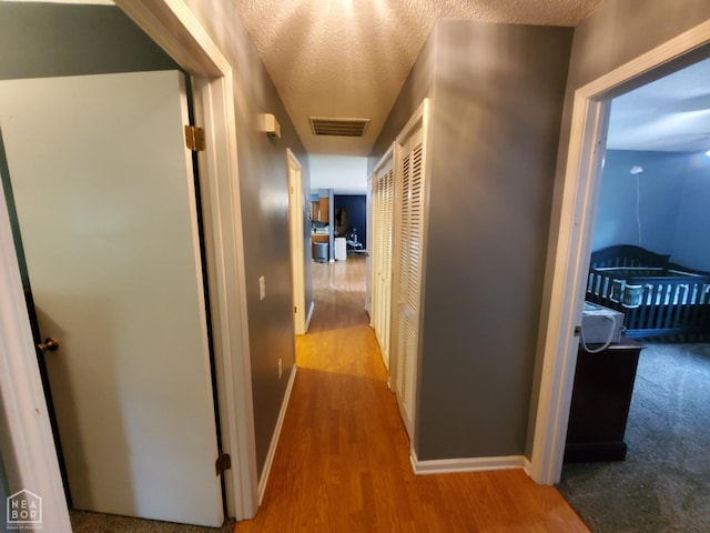 800 Hilltop Dr, Piggott, AR 72454 - corridor featuring wood finished floors, baseboards, and a textured ceiling