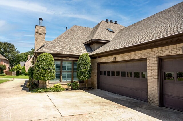 1203 Dove Rd, Jonesboro, AR 72401 - view of home's exterior with roof with shingles, a chimney, brick siding, and driveway
