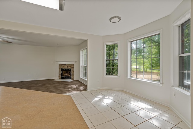 4604 Stillwater, Jonesboro, AR 72404 - unfurnished living room featuring light tile patterned floors, baseboards, a fireplace, and ceiling fan