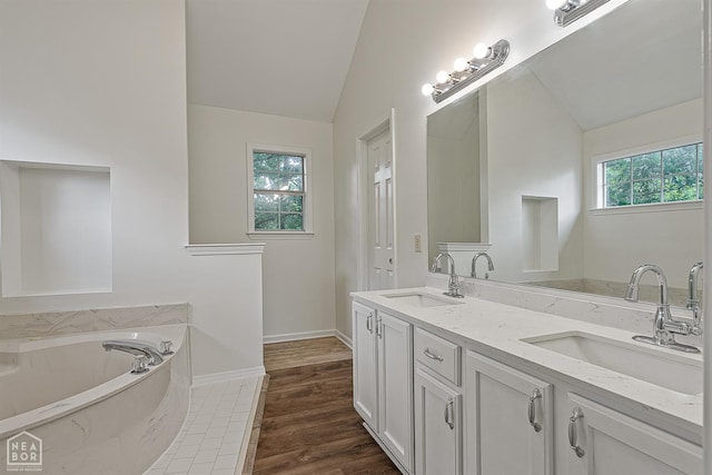 4604 Stillwater, Jonesboro, AR 72404 - bathroom featuring lofted ceiling, healthy amount of natural light, double vanity, a garden tub, and baseboards