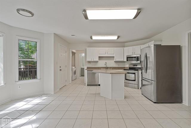 4604 Stillwater, Jonesboro, AR 72404 - kitchen with stainless steel appliances, a kitchen island, a sink, washer and dryer, and white cabinetry