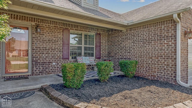 5007 S 28th St, Paragould, AR 72450 - doorway to property featuring brick siding, roof with shingles, and a garage