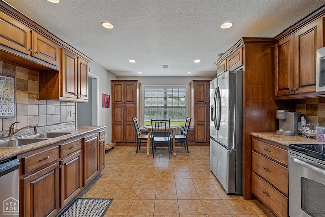 5007 S 28th St, Paragould, AR 72450 - kitchen with stainless steel appliances, a sink, tasteful backsplash, brown cabinetry, and recessed lighting