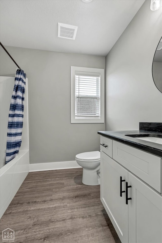 bathroom featuring shower / bath combo, toilet, visible vents, wood finished floors, and vanity