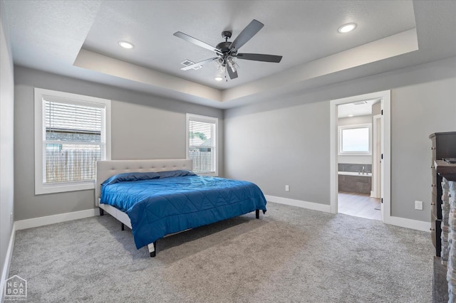 carpeted bedroom with baseboards, recessed lighting, a ceiling fan, connected bathroom, and a raised ceiling