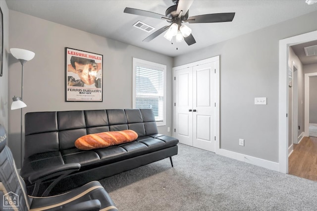 carpeted living area featuring ceiling fan, baseboards, and visible vents