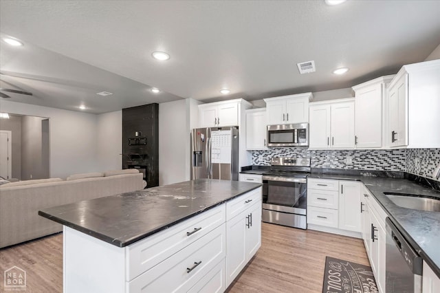 kitchen with stainless steel appliances, visible vents, a sink, decorative backsplash, and open floor plan