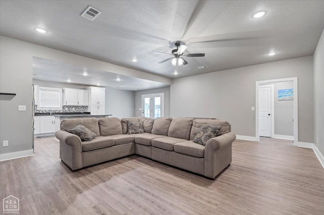 living room with baseboards, light wood-style flooring, visible vents, and ceiling fan