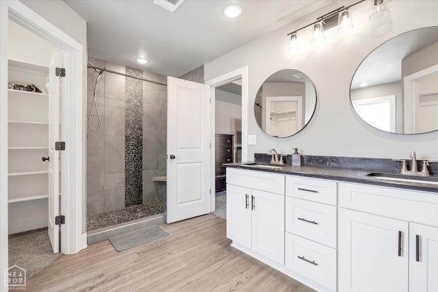 bathroom with a spacious closet, a sink, and tiled shower
