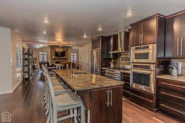 106 Winston Pl, Paragould, AR 72450 - kitchen featuring stainless steel appliances, wall chimney exhaust hood, a sink, open floor plan, and dark wood-style floors